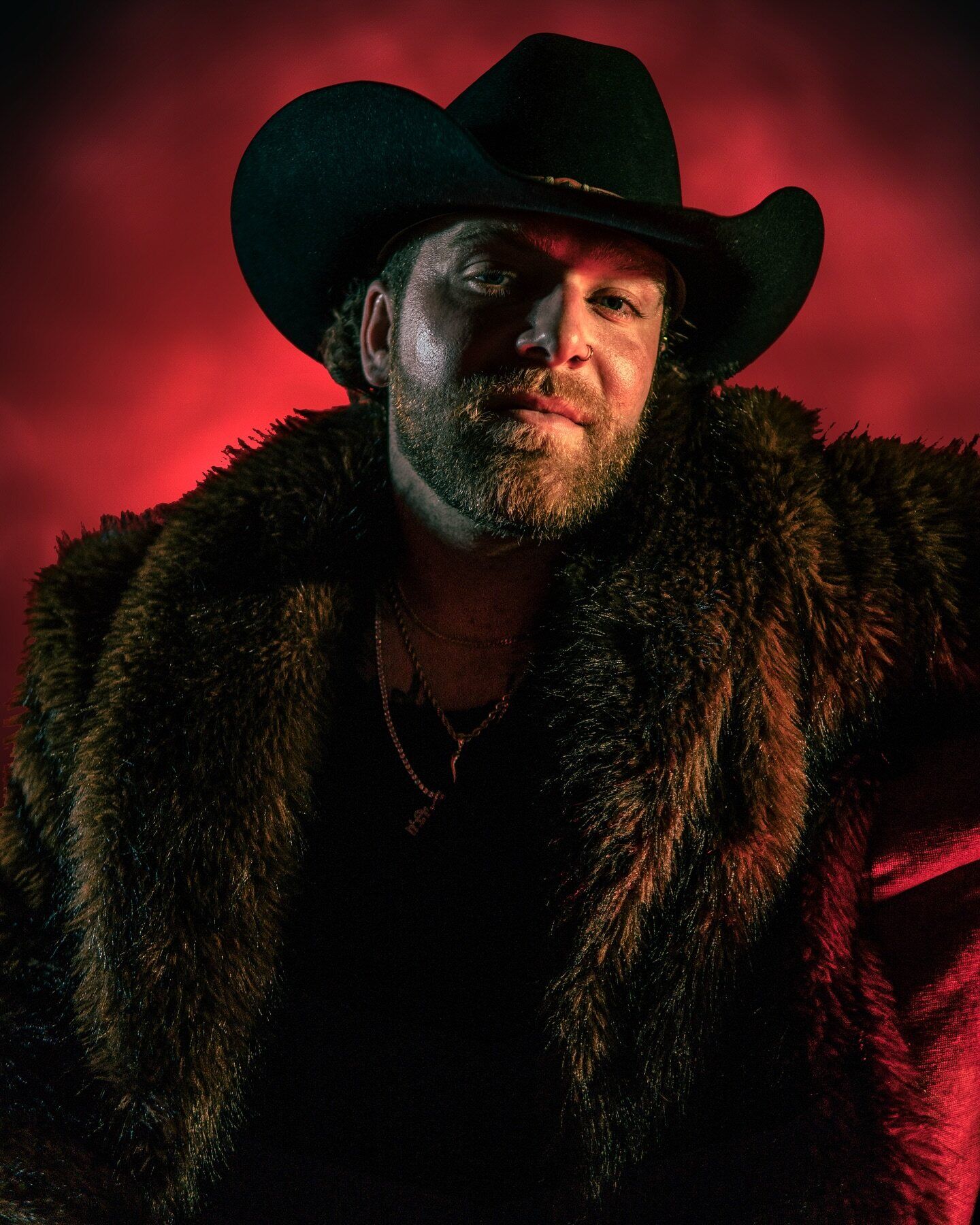 Dom in a black cowboy hat under red studio lighting