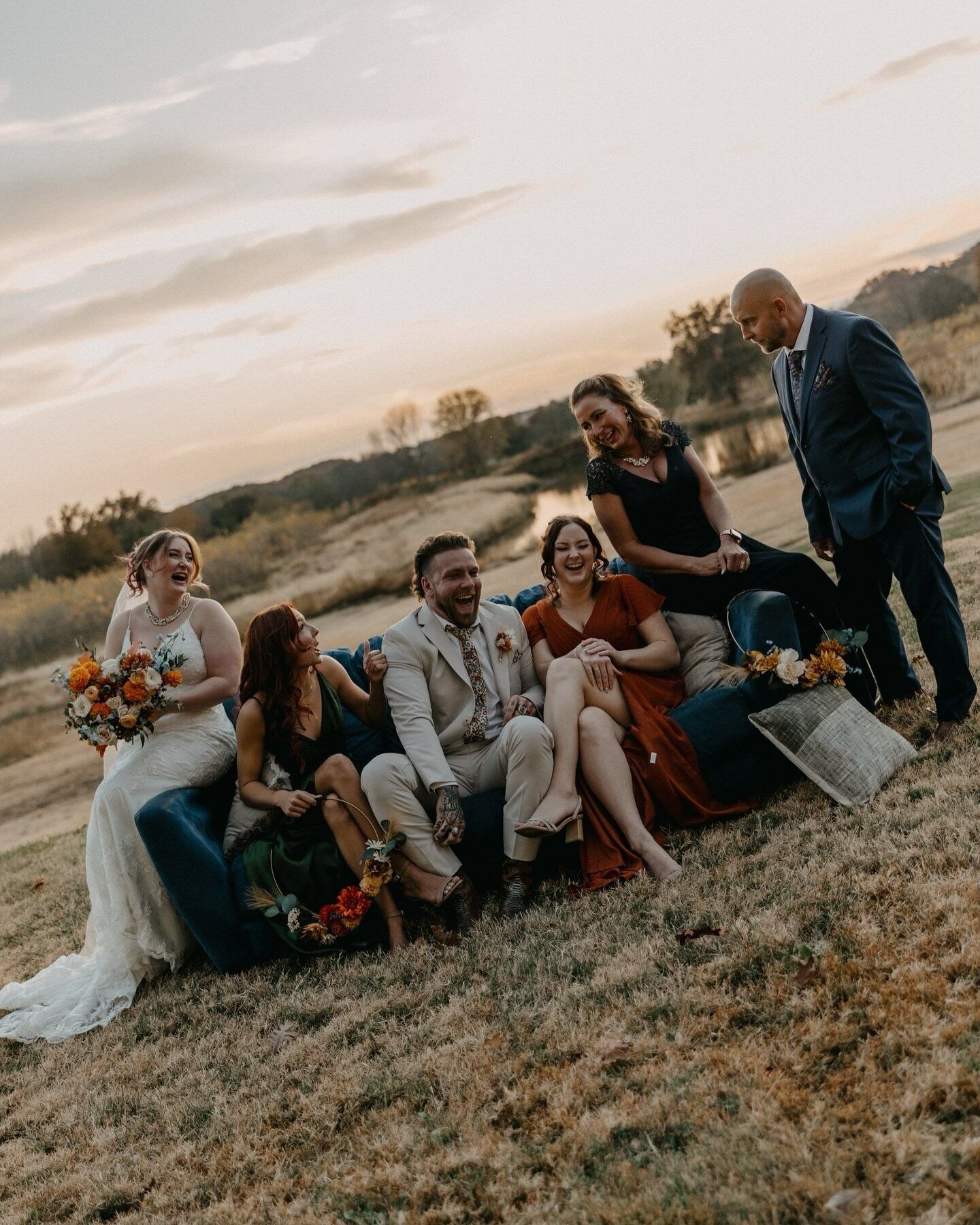 A wedding party laughing together outdoors at sunset